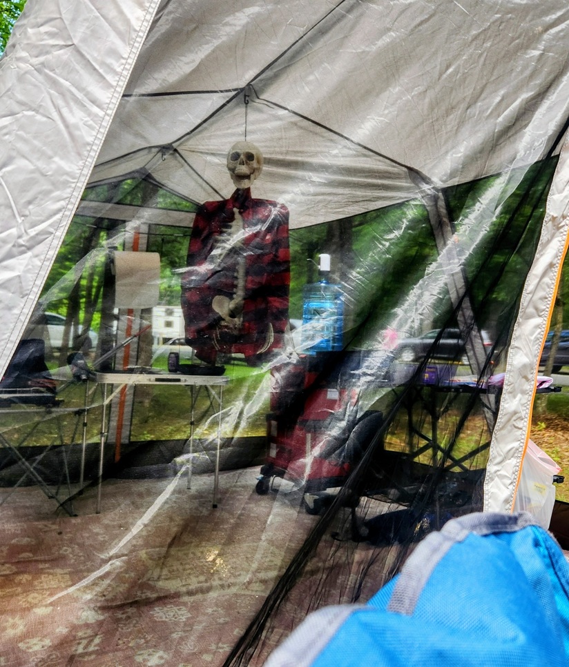 skeleton prop with no legs hanging from a patio tent outside